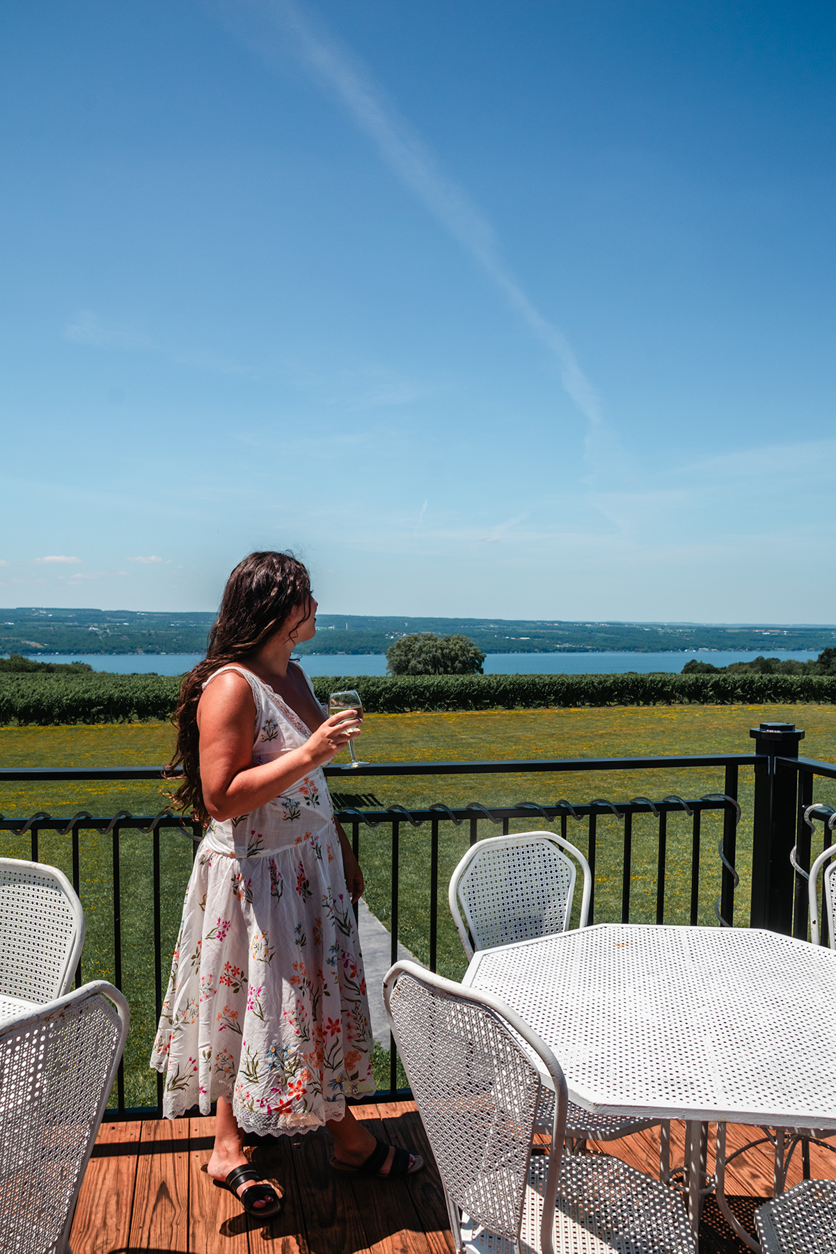 girl in a white dress holding glass of wine at Ginny Lee Cafe at Wagner Vineyards