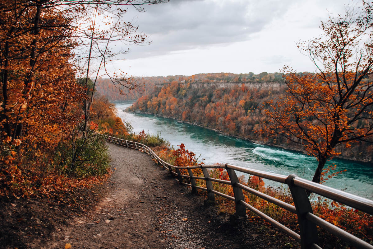 Calm section of the Niagara River reflecting fiery fall foliage on both banks.
