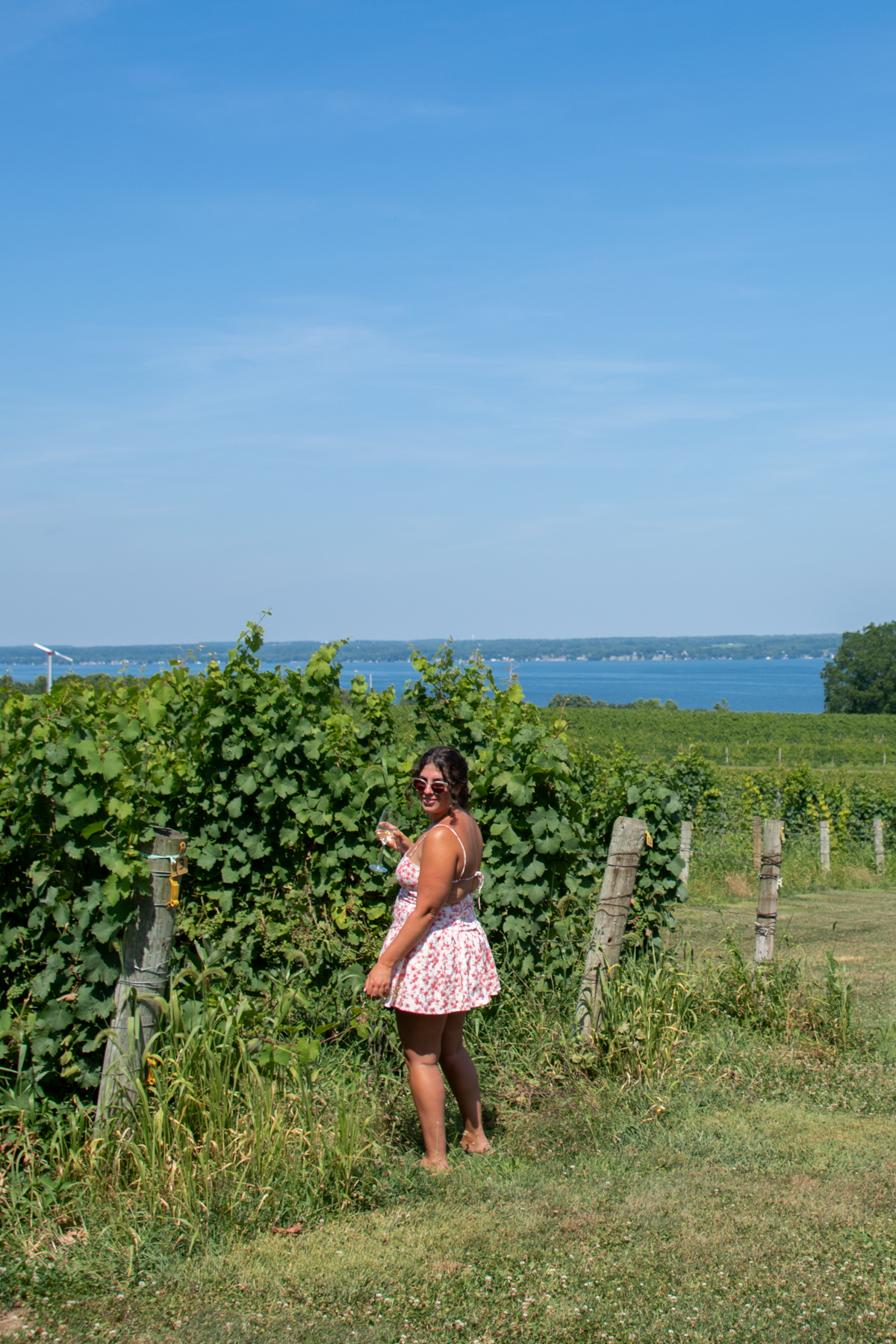 Close-up of woman in a floral dress enjoying wine among the grapevines at Fox Run Vineyards.