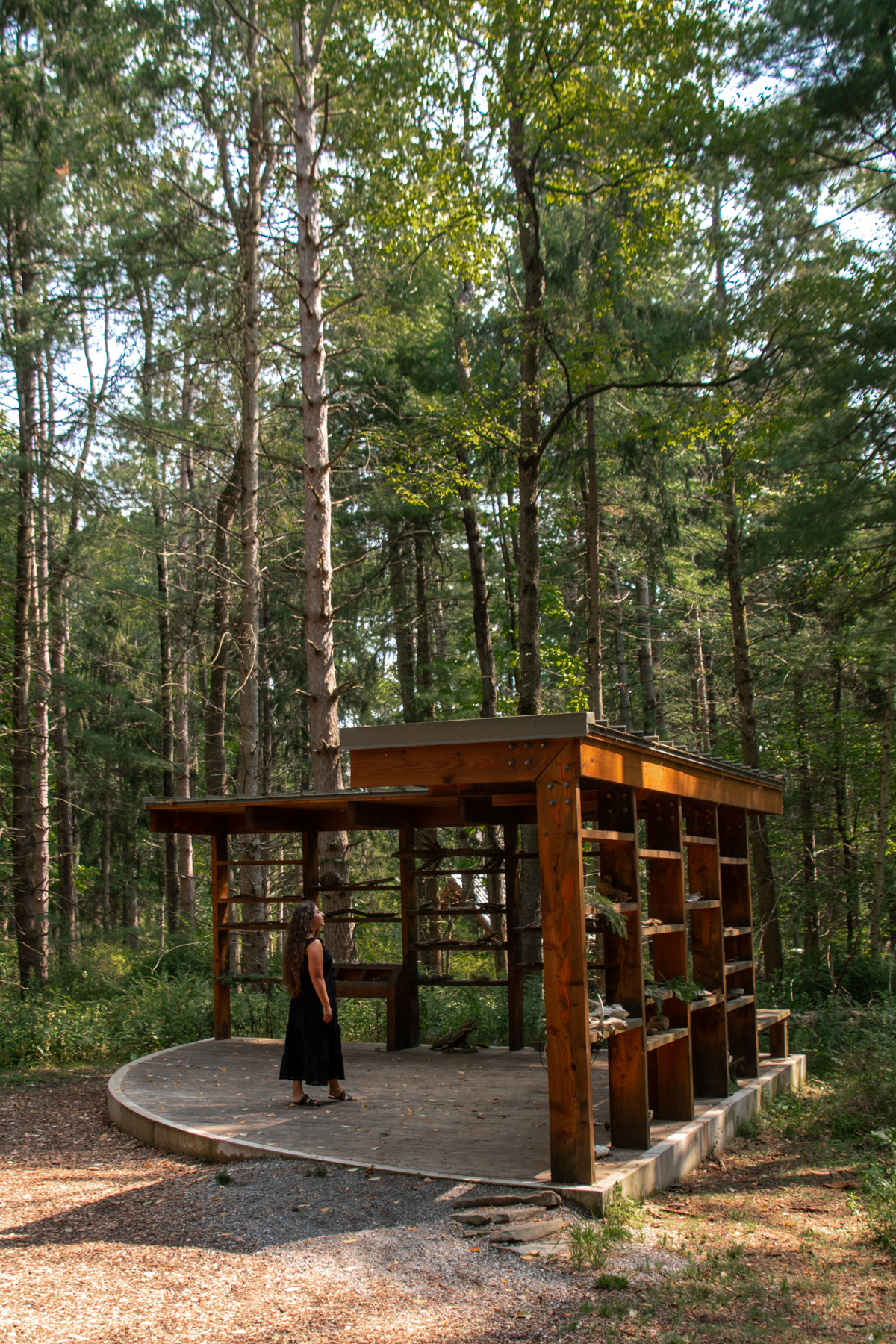 Interactive nature station on the Autism Nature Trail – Wooden structure with shelves for natural objects, where a visitor explores tactile exhibits designed to engage the senses.