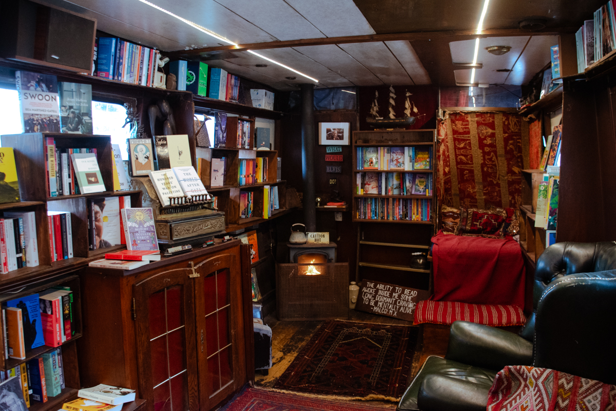 Warm and inviting interior of Word on the Water with bookshelves, fireplace, and reading nook aboard the London book barge