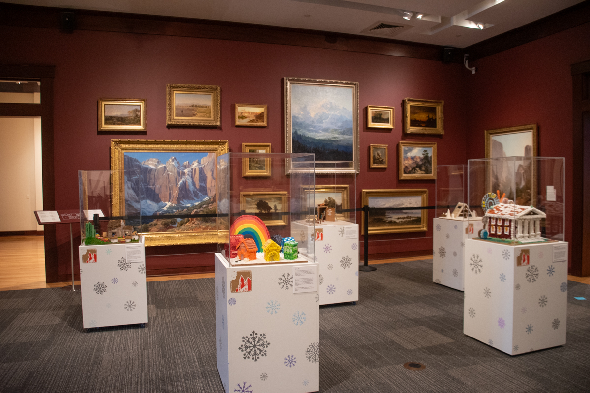 Gingerbread Invitational display at The Rockwell Museum in Corning, NY, featuring colorful gingerbread creations on decorated pedestals surrounded by Western and landscape paintings.