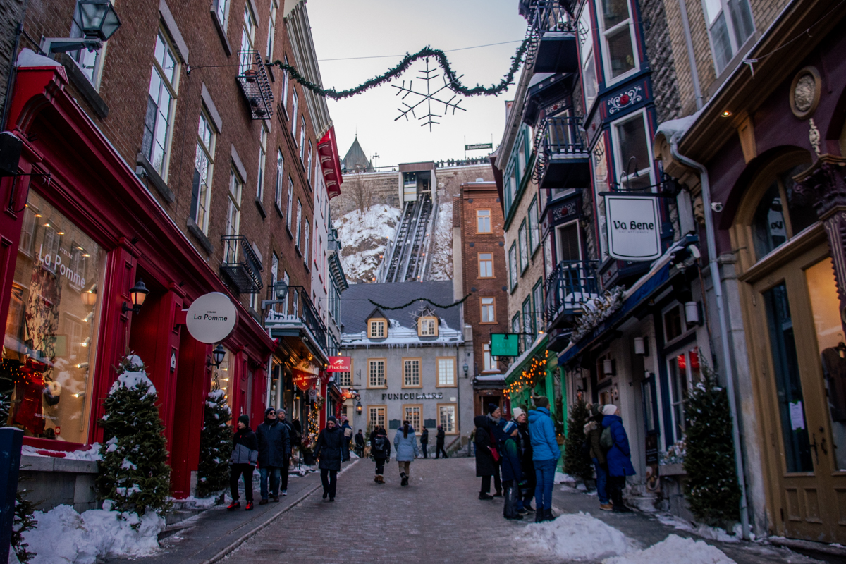 Snowy Rue du Petit-Champlain in Old Quebec City with the funicular visible in the background during winter.