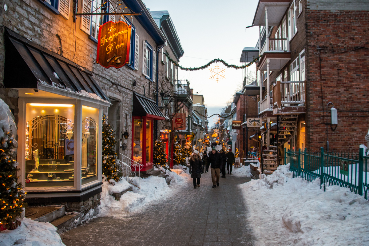 Rue du Petit-Champlain lined with snow and glowing storefronts in Old Quebec City during winter.
