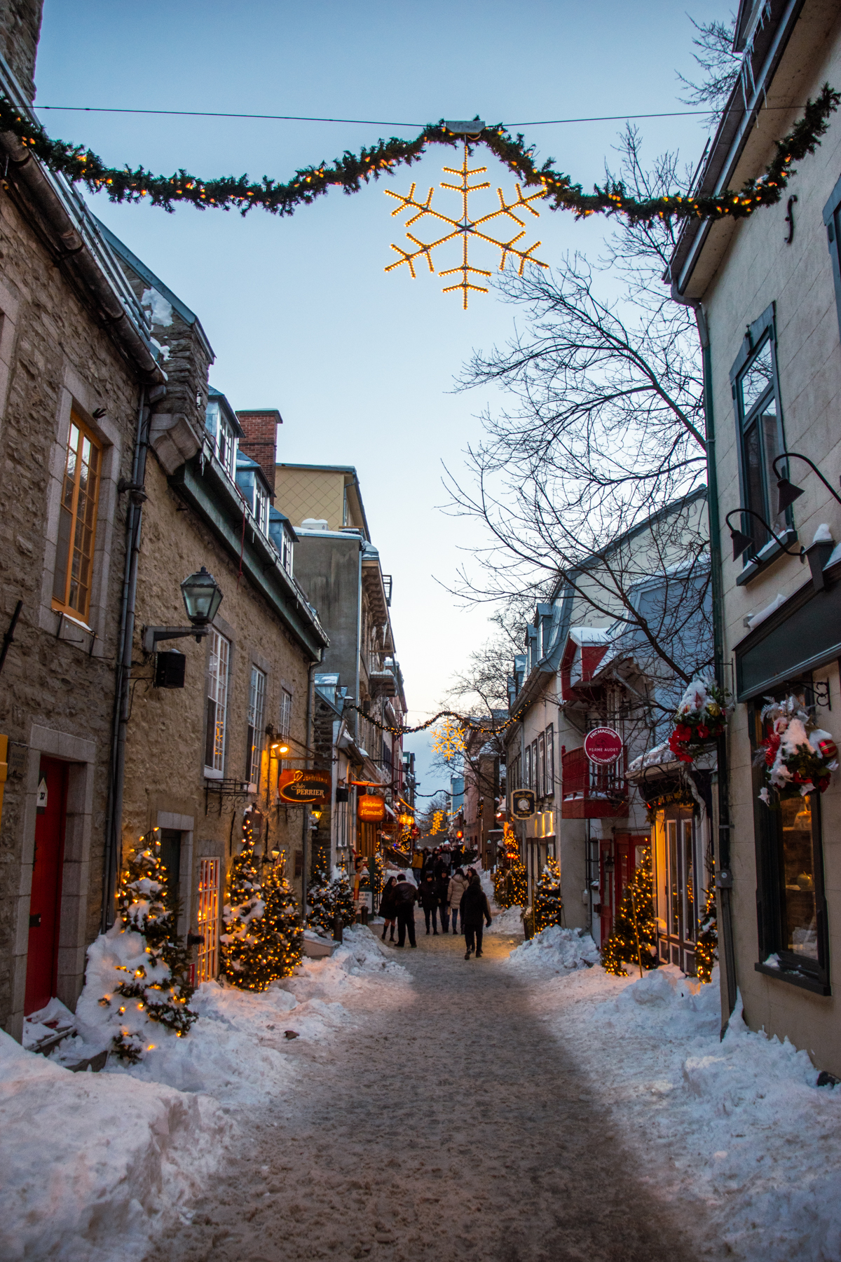 Snow-covered Rue du Petit-Champlain decorated with illuminated snowflakes and garlands in Old Quebec City.