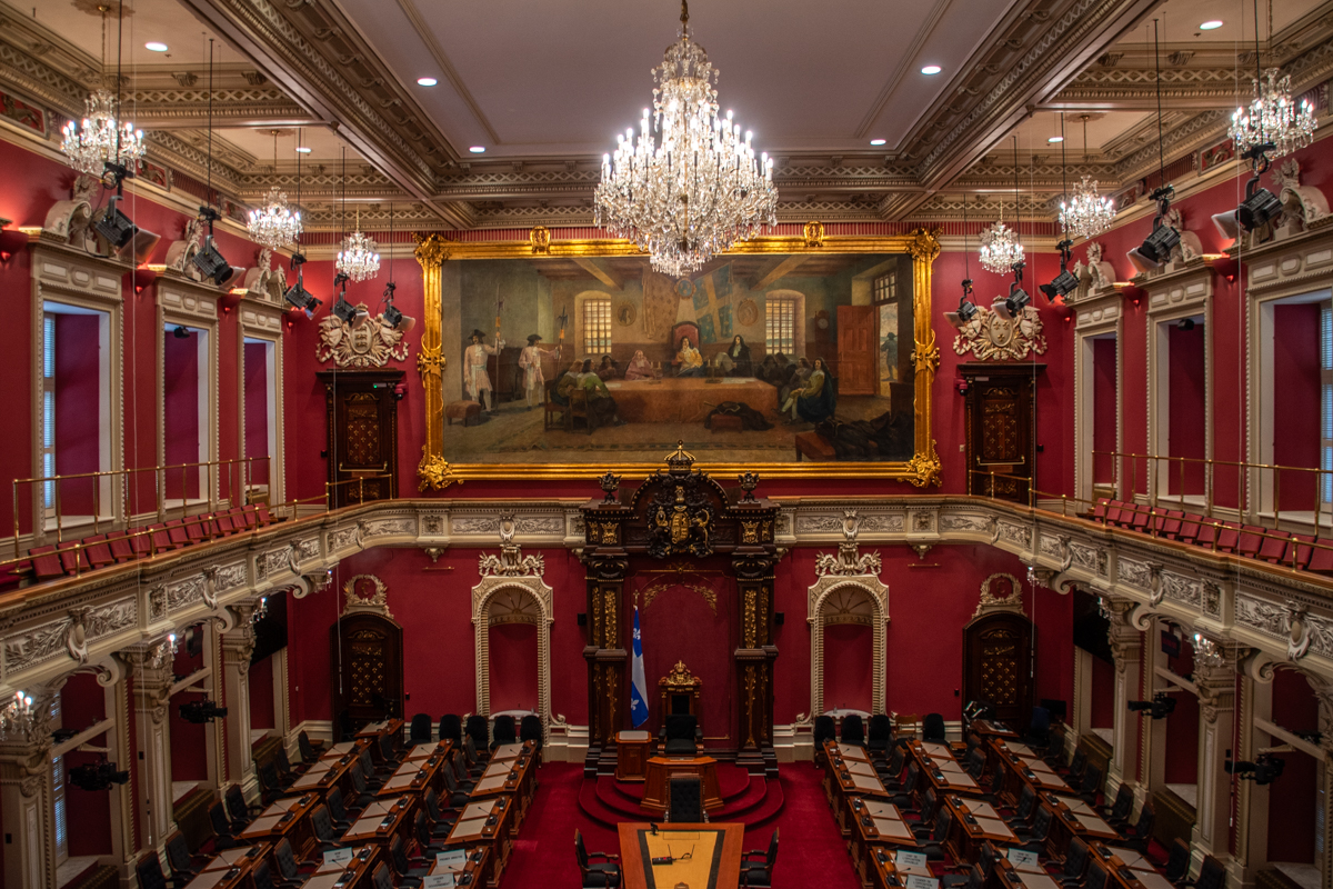 Interior of the National Assembly of Quebec in Quebec City, featuring red walls, chandeliers, and historic architecture, a cultural stop during winter in Quebec City.