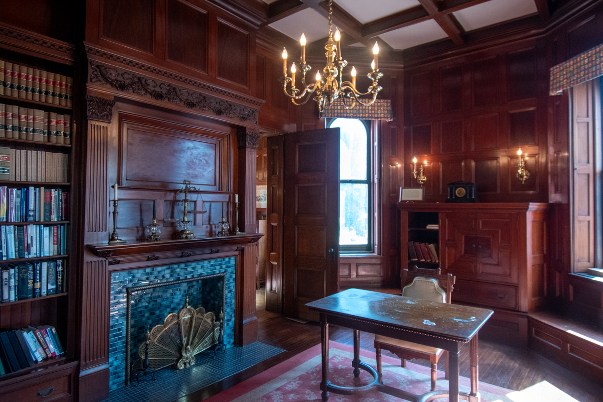 Historic library with wood-paneled walls, built-in bookshelves, and a decorative fireplace inside the Robert H. Jackson Center.
