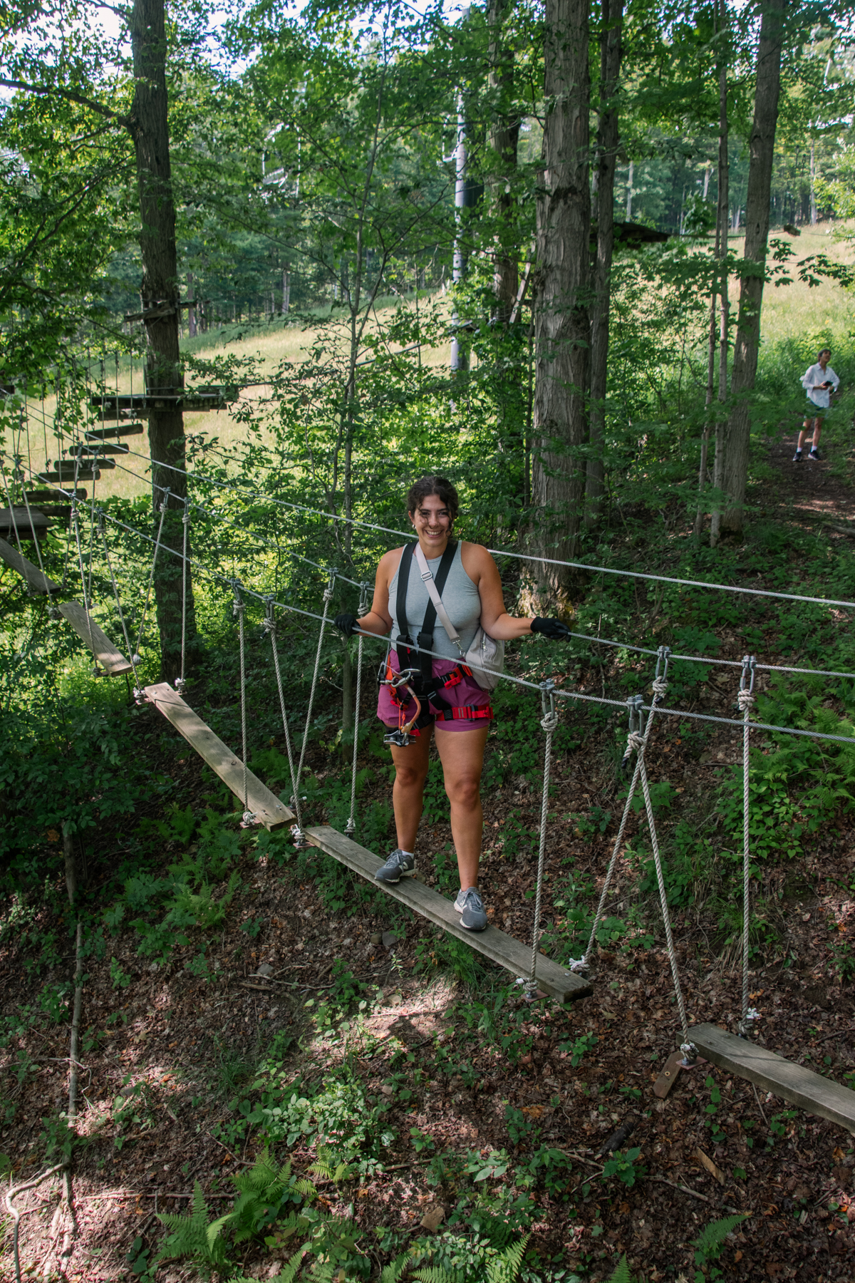 Visitor crossing a suspended rope bridge during the aerial adventure course at Peek'n Peak Mountain Adventures.