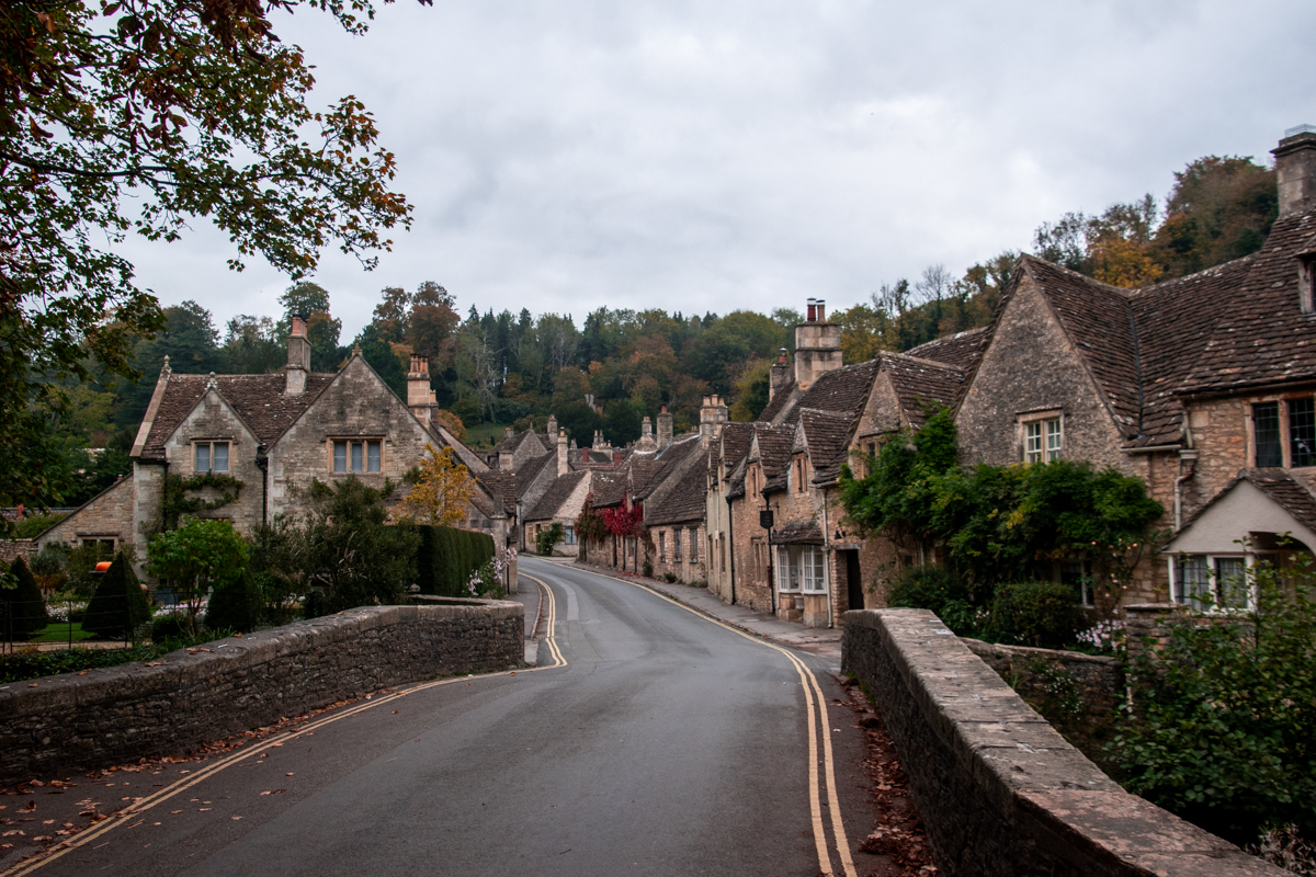 Picturesque road winding past historic stone cottages in Castle Combe, Cotswolds.
