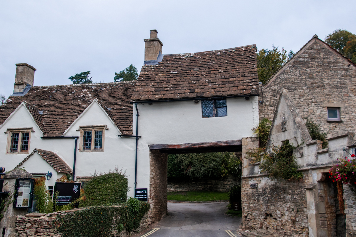Historic stone buildings and covered archway along a street in Castle Combe, England.